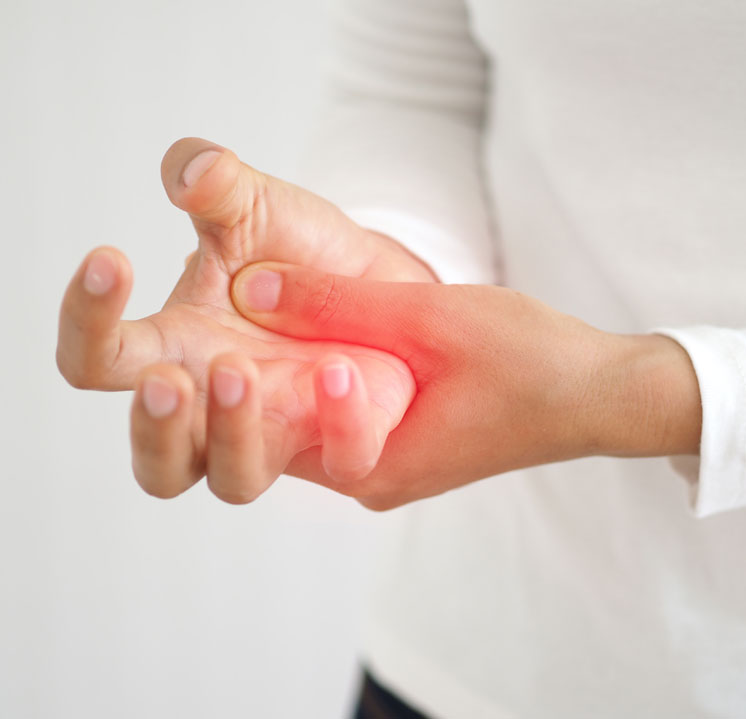 A close-up of a person grasping their hand, with a red highlight over the thumb joint and palm to indicate pain and inflammation from arthritis.