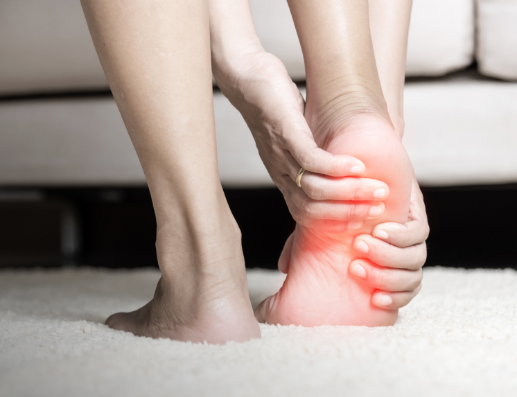 A close-up of a person holding the heel of their foot to show discomfort, with a red highlight indicating a point of chronic pain or inflammation from a condition like plantar fasciitis.